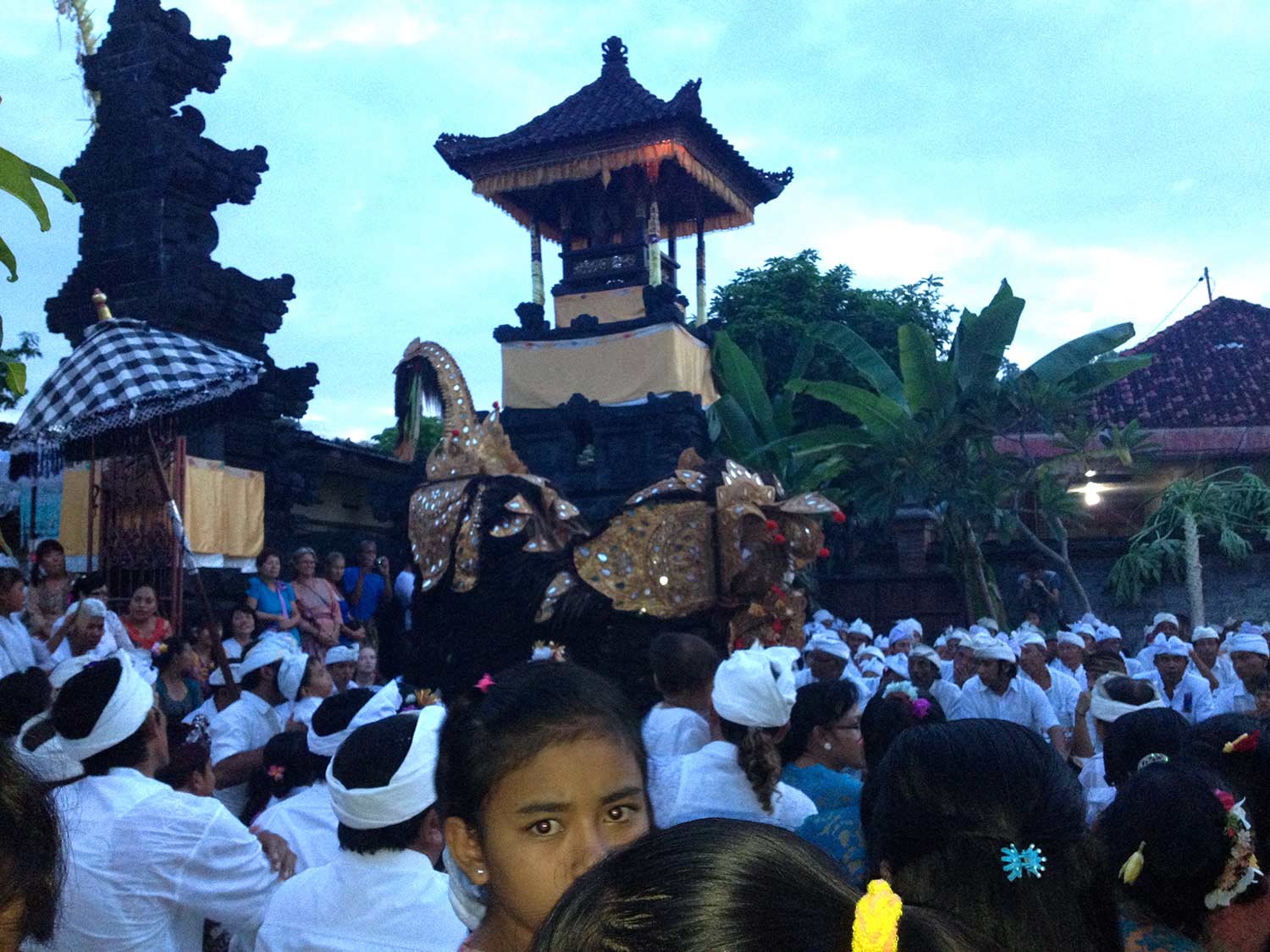 A dense group of people on the streets of Bali watching a procession